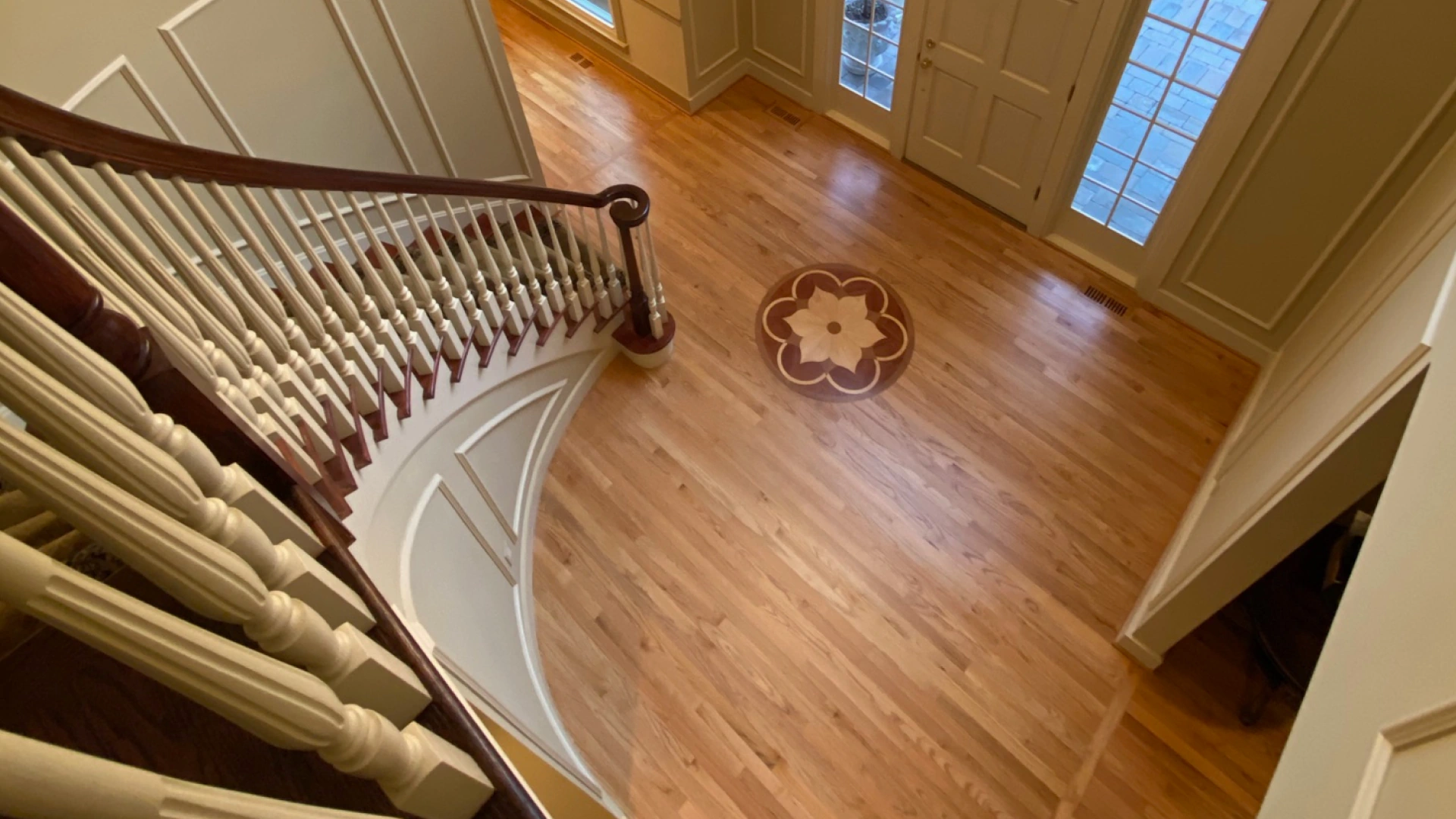 Curved staircase and hardwood entry floor with inlaid medallion installed by Hardwood Kings in Leawood, Kansas