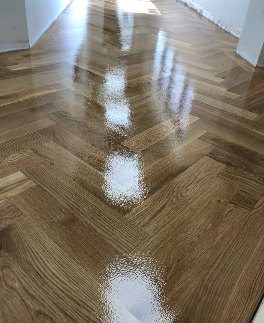 Hardwood floor mid-refinish showing fresh stain being applied